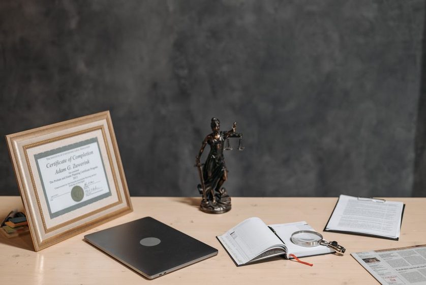 An open notebook and a stack of printed articles on a plain desk